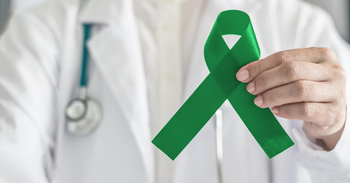 Emerald green or jade color ribbon in doctor's hand symbolic for Liver Cancer and Hepatitis B disease awareness concept